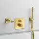 Wandmontierte Armatur in gebürstetem Gold von Ideal Standard, bestehend aus Wasserhahn, Thermostat und Handbrause, angeordnet an einer hellen Wand.